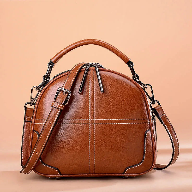 Round leather handbag with soft double handles and zipper closure in wine red colour
