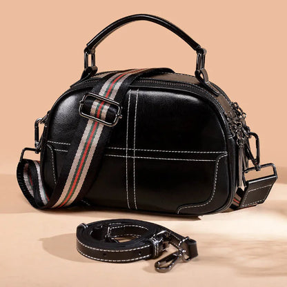 Round leather handbag with soft double handles and zipper closure in wine red colour
