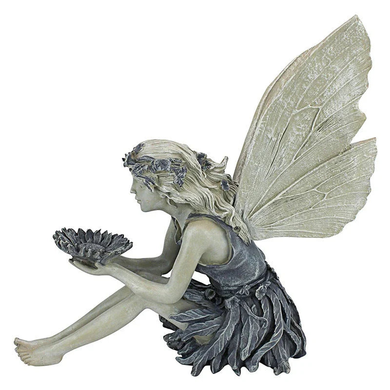 Beautifully detailed fairy statue with flower crown and petal skirt, holding a sunflower bowl in a garden setting