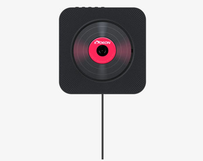 Wall-mounted tray-loading CD player in white colour with remote control on a wooden wall.