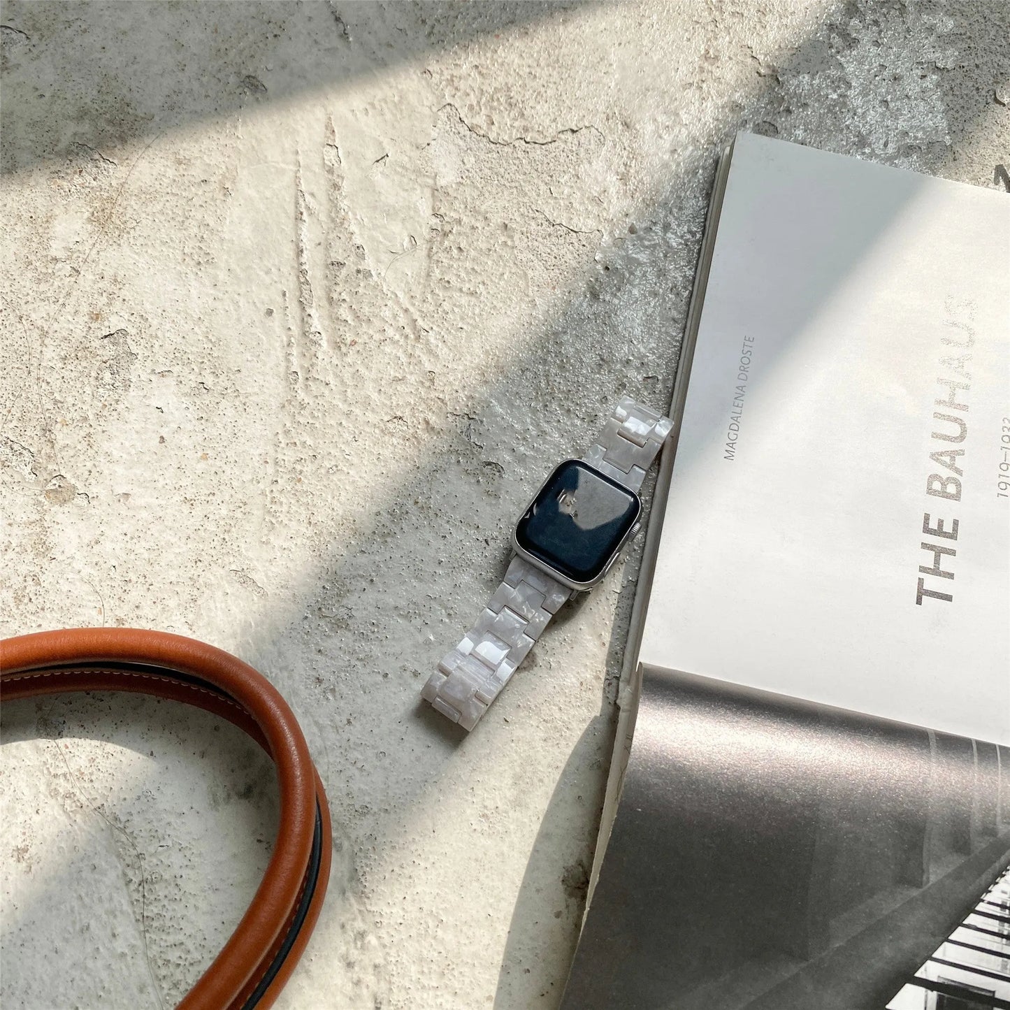 White and grey shell pattern resin Apple Watch strap on a wrist.