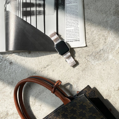 White and grey shell pattern resin Apple Watch strap on a wrist.