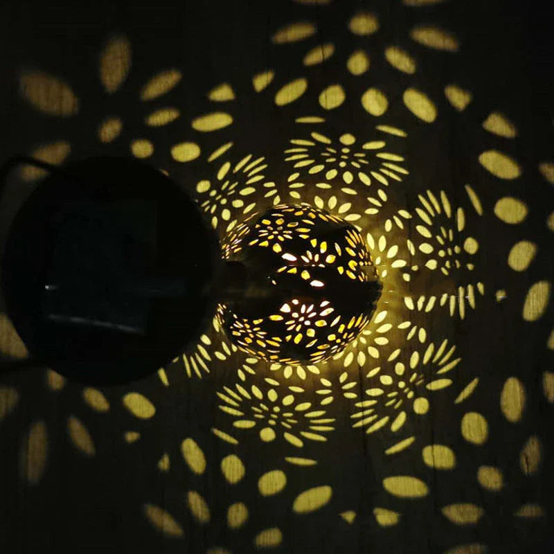Elegant solar-powered garden lantern with a drop-shaped metal design and a soft, flower-patterned glow