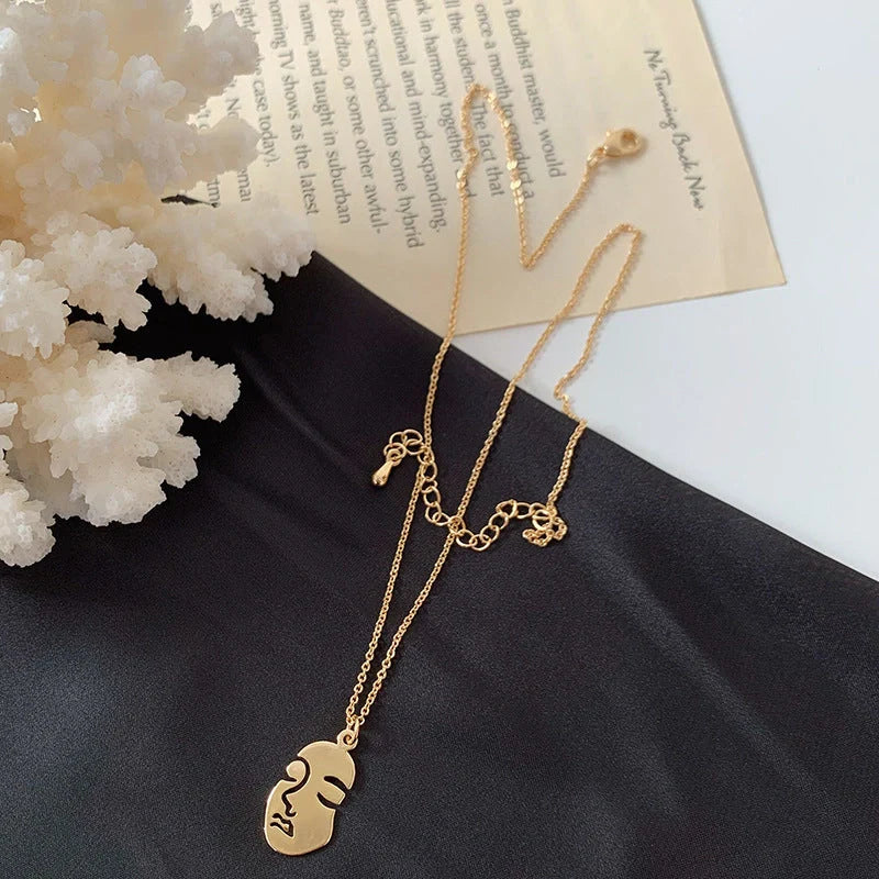 Gold alloy abstract face choker necklace with geometric pendant, adjustable length