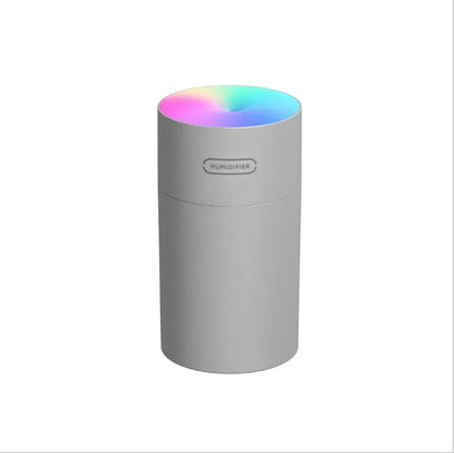 Pink USB desktop humidifier with LED lights and water tank on wooden desk