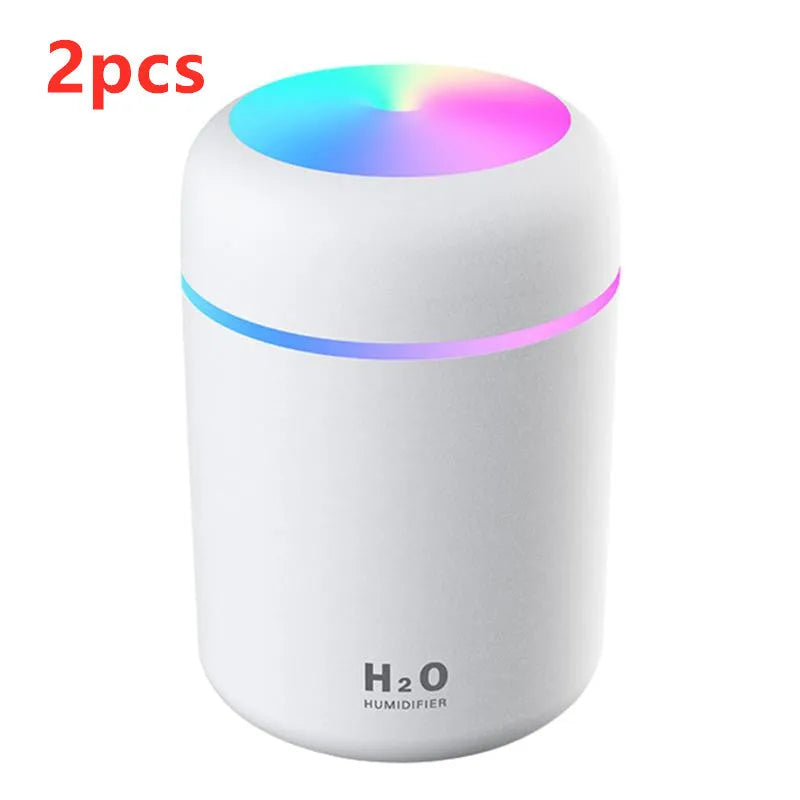 Pink USB desktop humidifier with LED lights and water tank on wooden desk