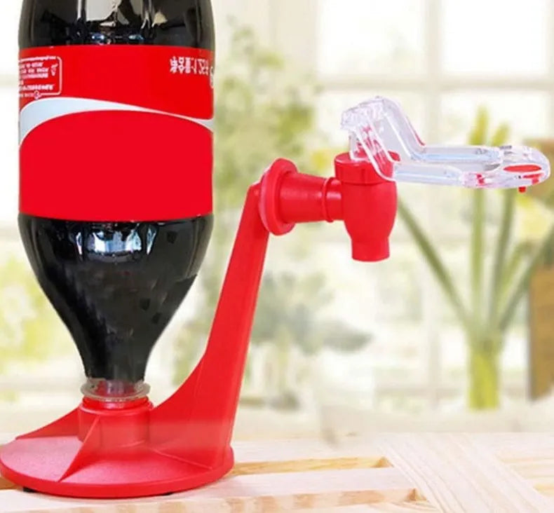 Red plastic Magic Tap soda bottle dispenser attached to an inverted 2-litre bottle on a kitchen table.