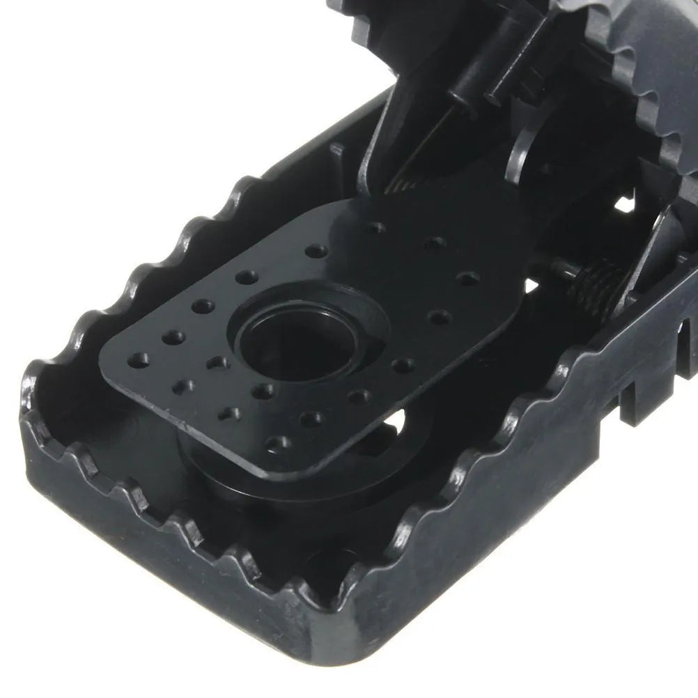 Six black plastic snapping mousetraps laid out on a surface, showing their size and smooth construction.