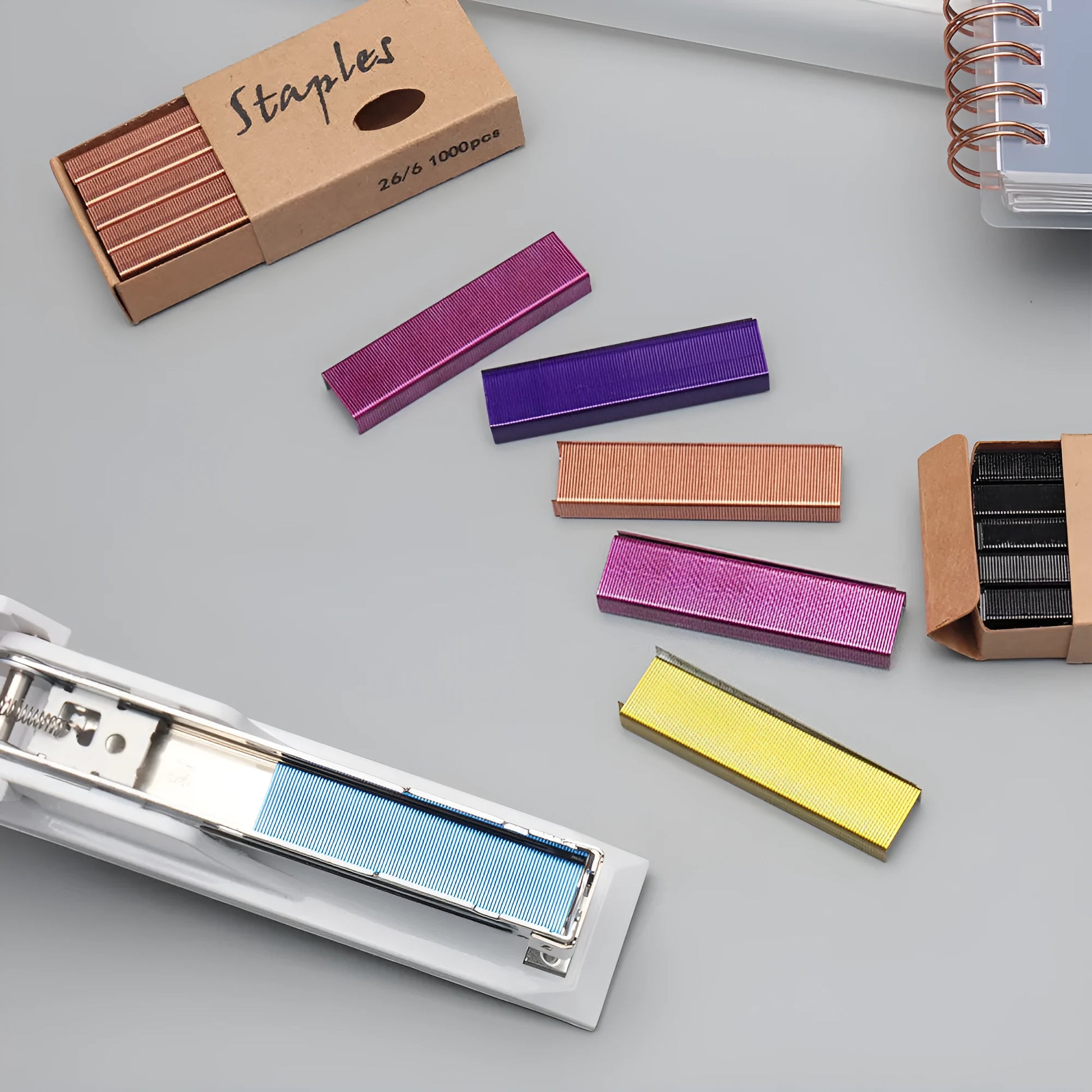 Box of 1000 metal stapling needles in rose gold, black, purple, and rose red colours.