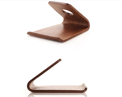 Solid wooden iPhone stand in Walnut finish on a desk, holding a mobile phone.