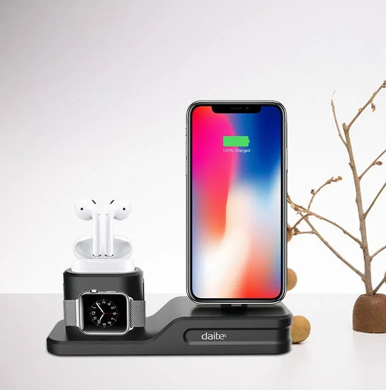 Black silicone 3-in-1 charging stand for Apple iPhone, Apple Watch, and AirPods on a desk