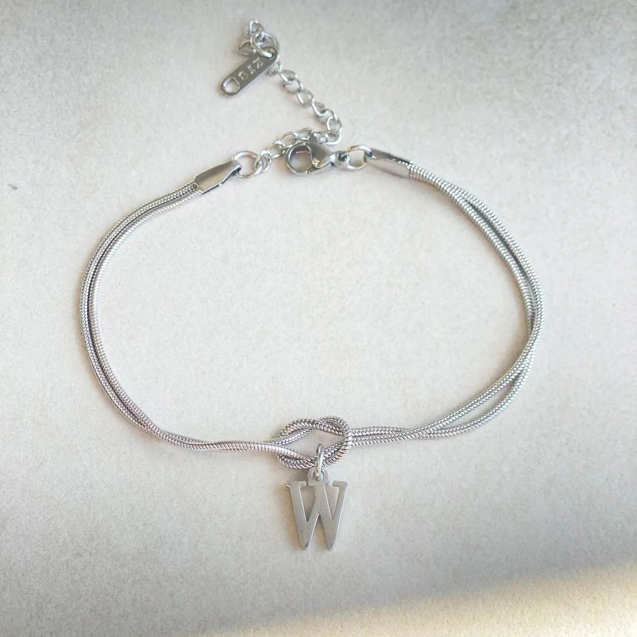 Elegant letter charm bracelets for women in gold and silver tones, featuring a delicate snake chain design and personalised letter charms.