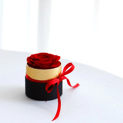 Luxury gift box containing an arrangement of preserved red eternal roses on a dark background.
