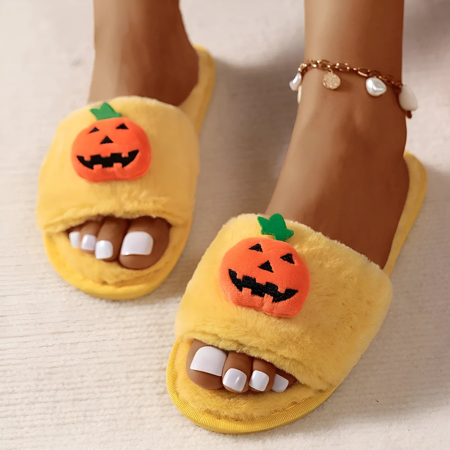 Yellow pumpkin plush open-toe slippers with cartoon design on a synthetic fur upper and textured PVC sole.