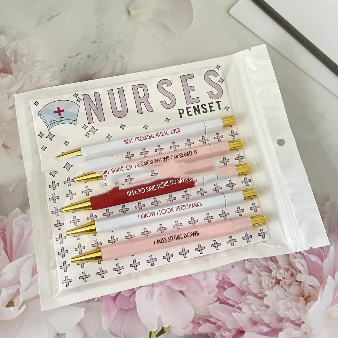 Set of five white plastic retractable ballpoint pens with blue and red nurse-themed text and graphics.
