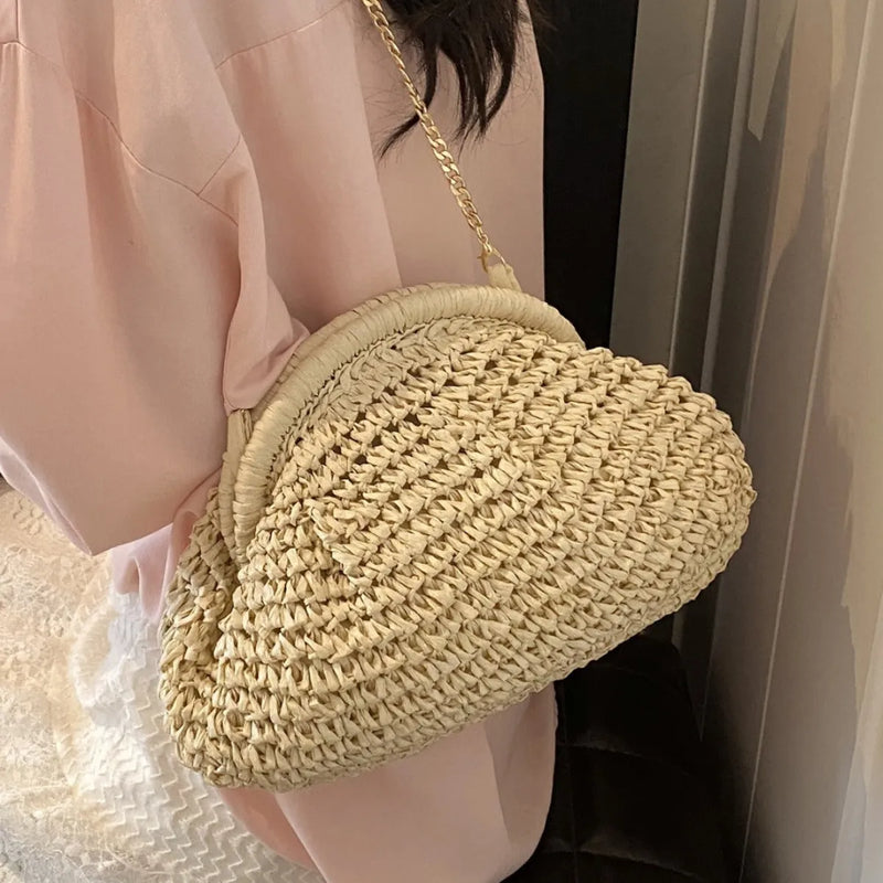Women's straw beach bag in paper material with khaki or milky white colour options, featuring a medium-soft shell shape design, internal zipped compartment, and chain strap details for daily use and beach vacation leisure.