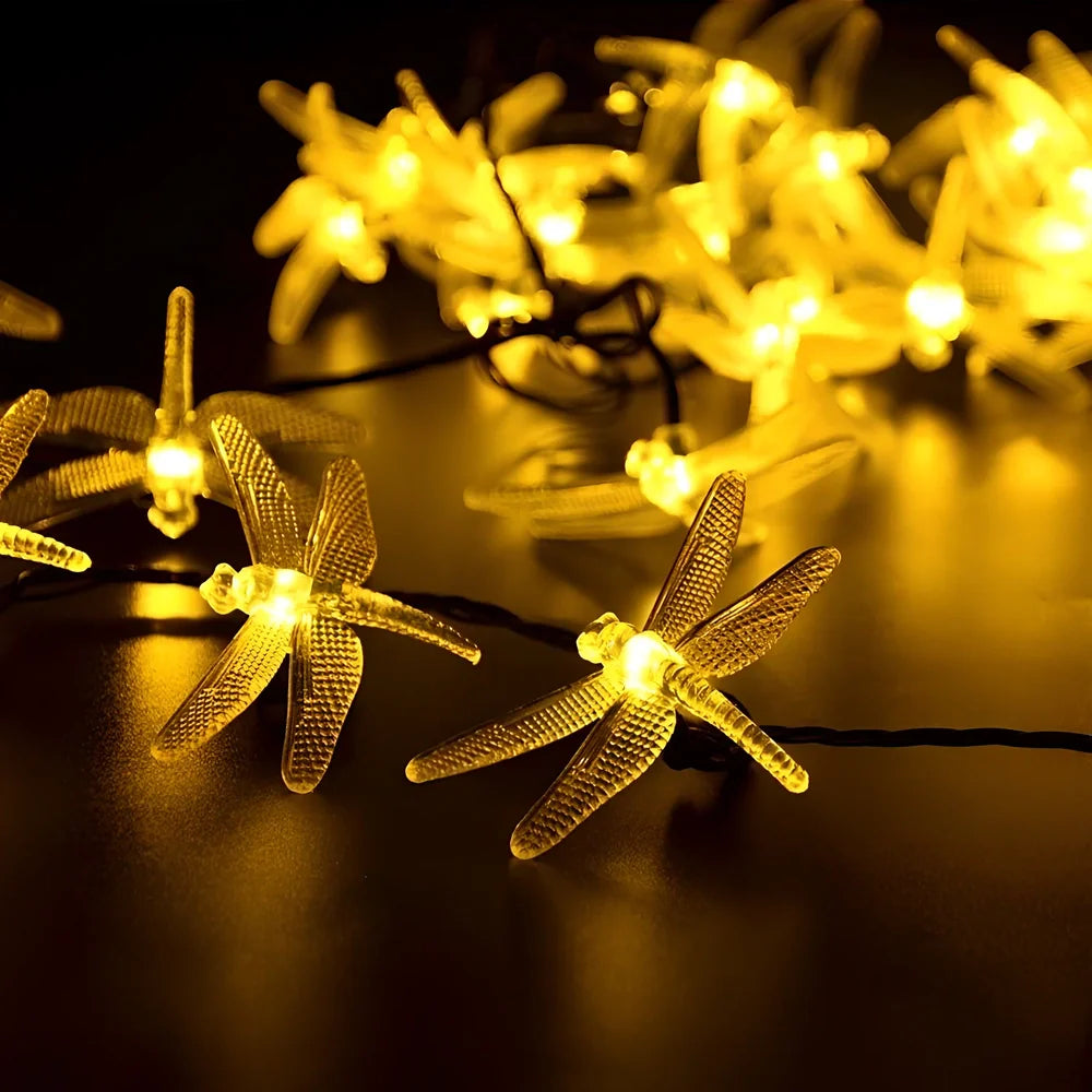 Solar-powered dragonfly string lights with 30 warm white LEDs in garden setting