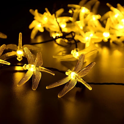 Solar-powered dragonfly string lights with 30 warm white LEDs in garden setting