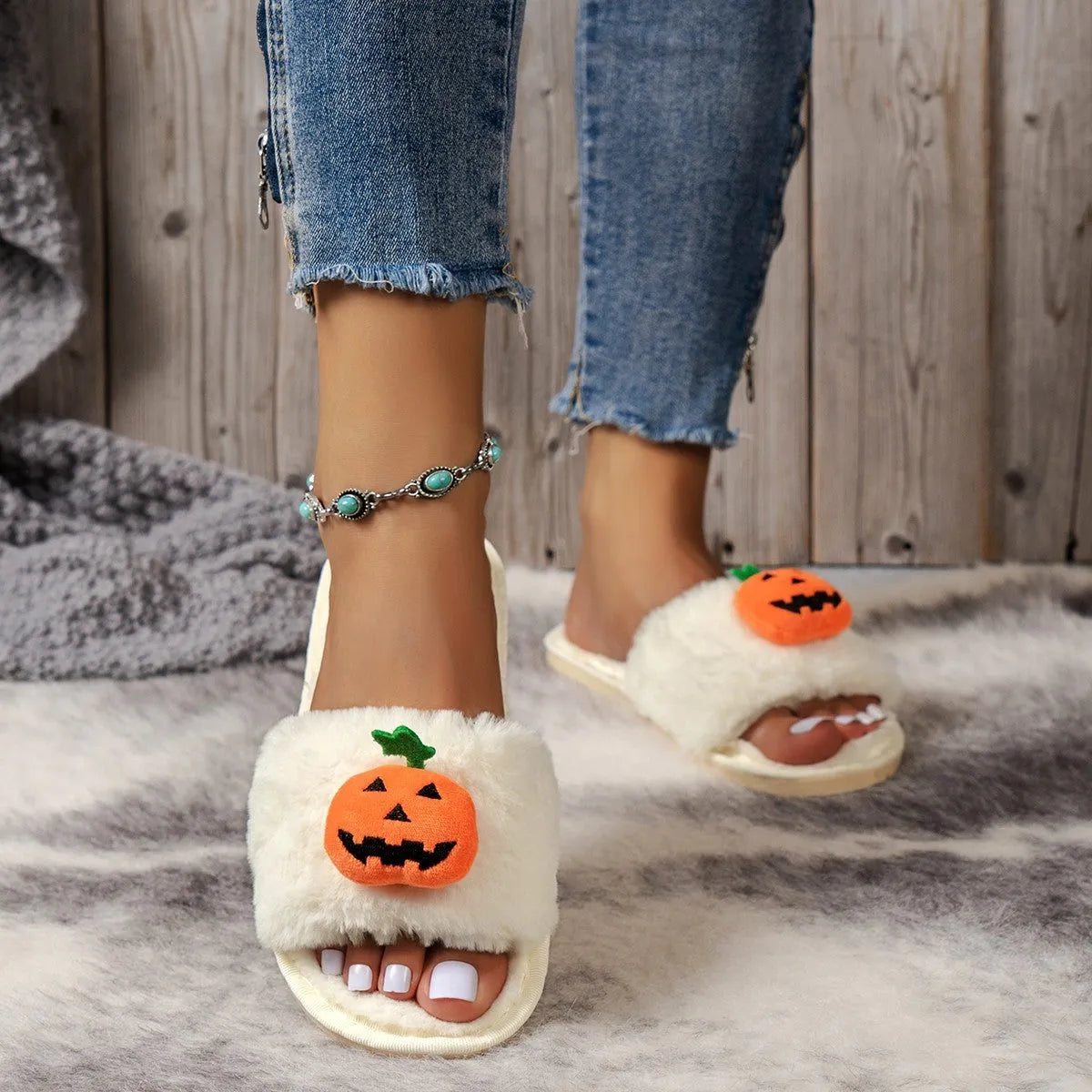 White and yellow plush pumpkin slippers with open toe and textured anti-slip sole on wooden floor.