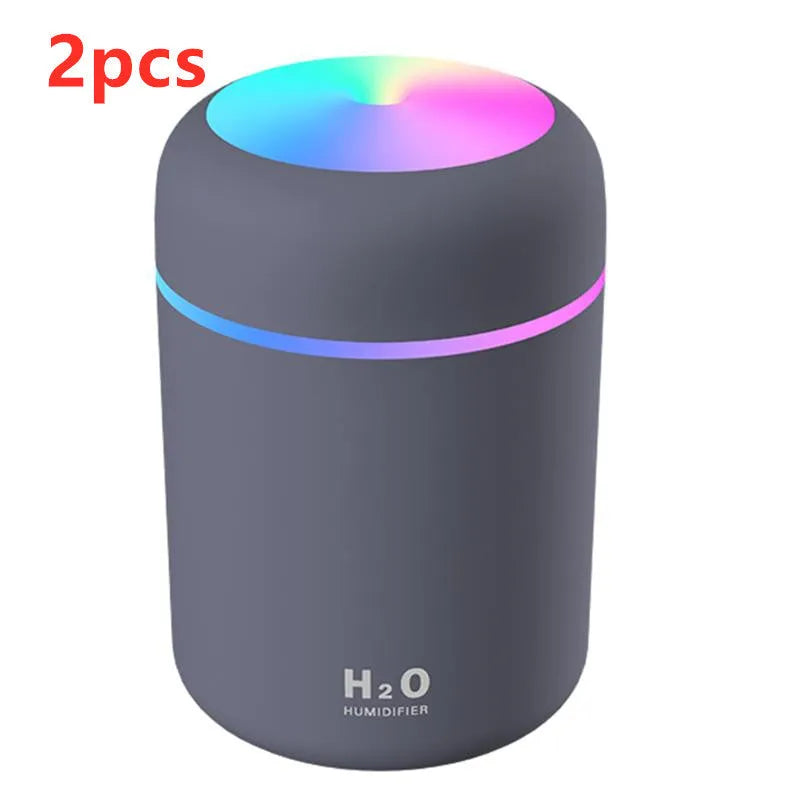 Pink USB desktop humidifier with LED lights and water tank on wooden desk
