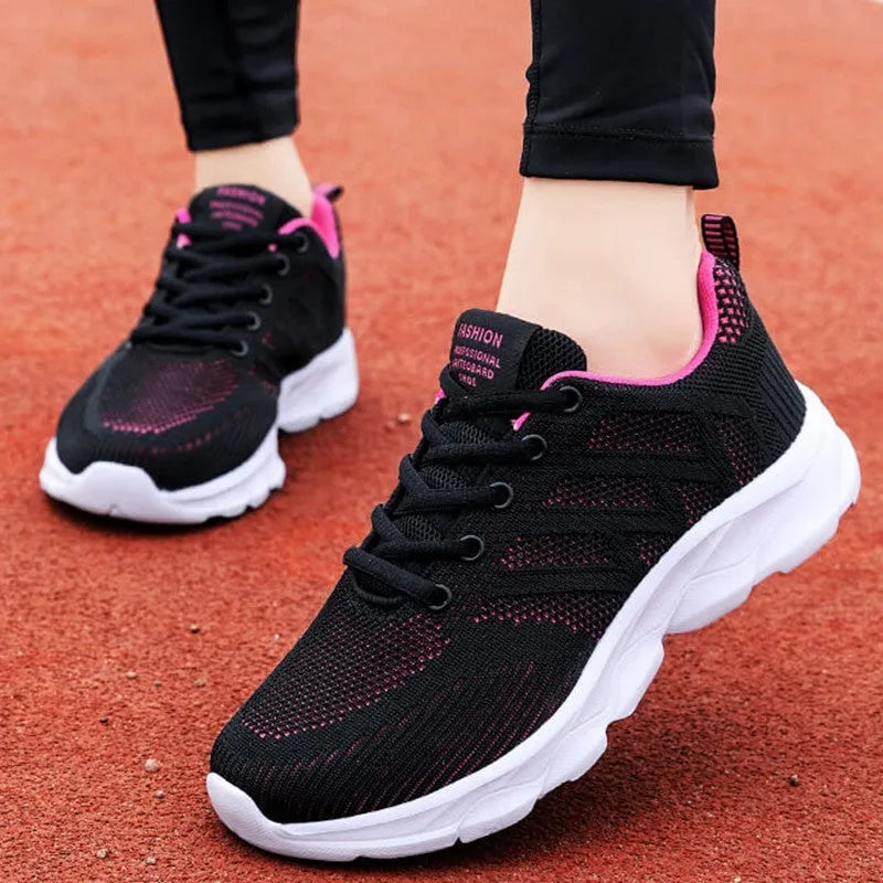 Women's white mesh leisure shoes with lace-up front and low heel on a neutral background.