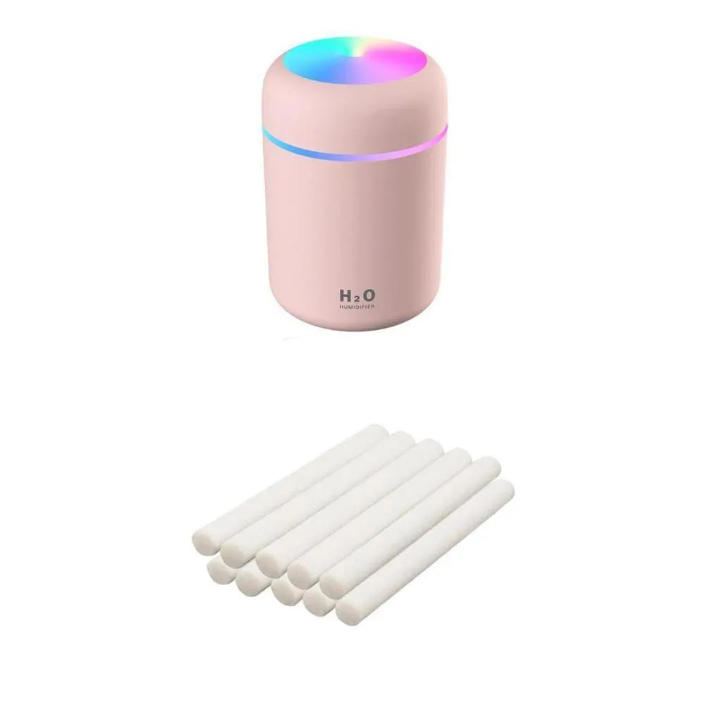 Pink USB desktop humidifier with LED lights and water tank on wooden desk