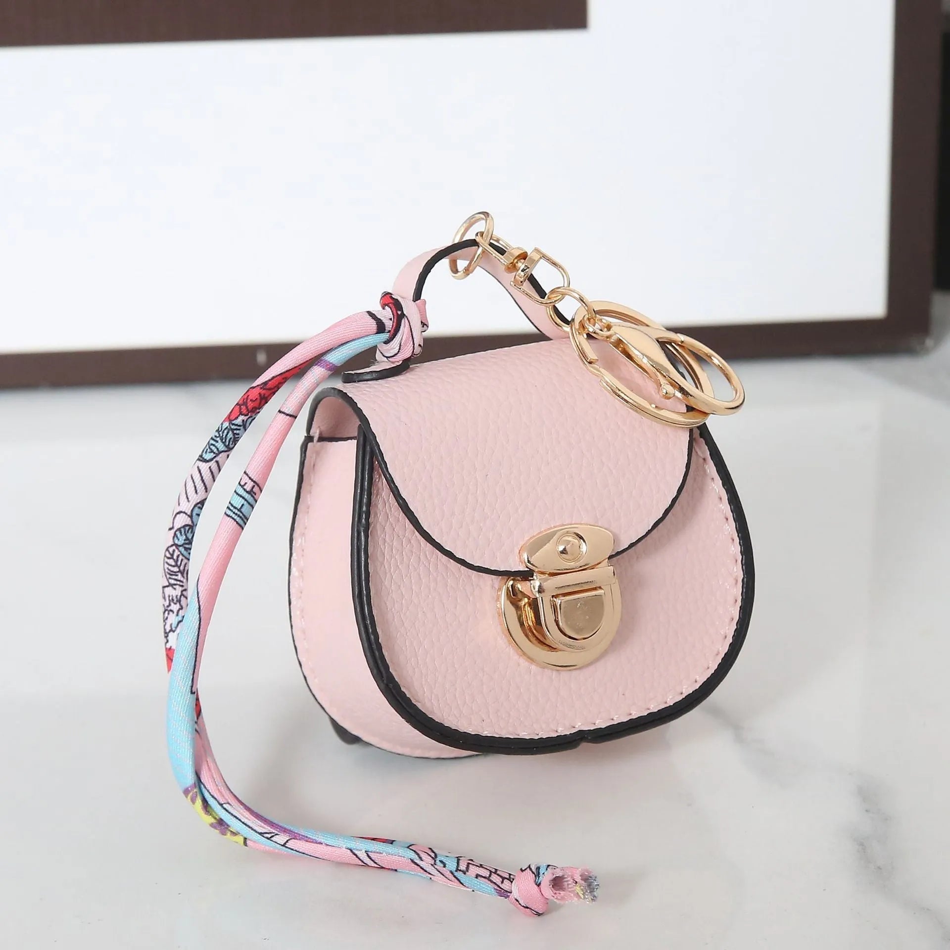 Solid colour PVC coin purse keychain shown in saddle bag black, orange, brown, red, grey, and pink.