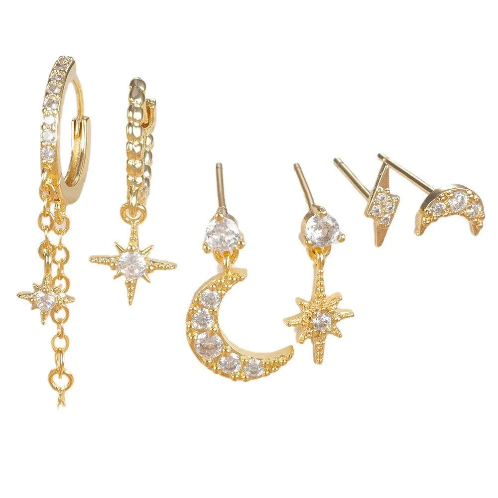 Set of six gold-coloured XINGX chain tassel stud earrings with zircon details on a flat surface.