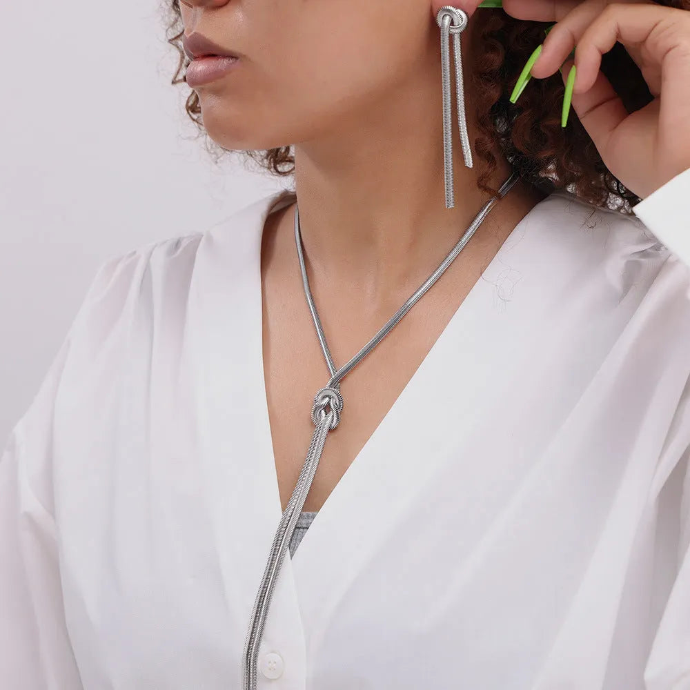 Gold electroplated titanium steel necklace with snake chain and knotted tassel pendant, shown with matching earrings.