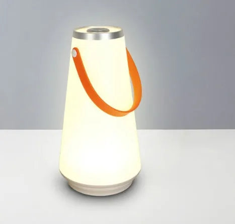 White rechargeable LED lantern with USB cable on a bedside table.