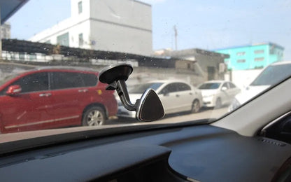 Black magnetic car phone holder with rotating head shown mounted on dashboard
