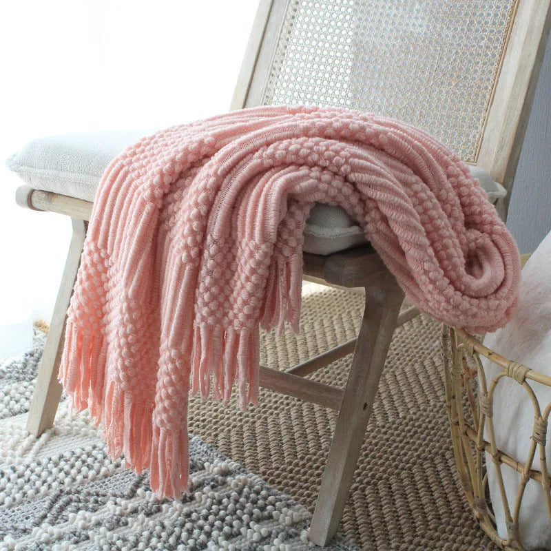 Nordic style knitted bubble texture blanket in light grey, draped over a sofa.