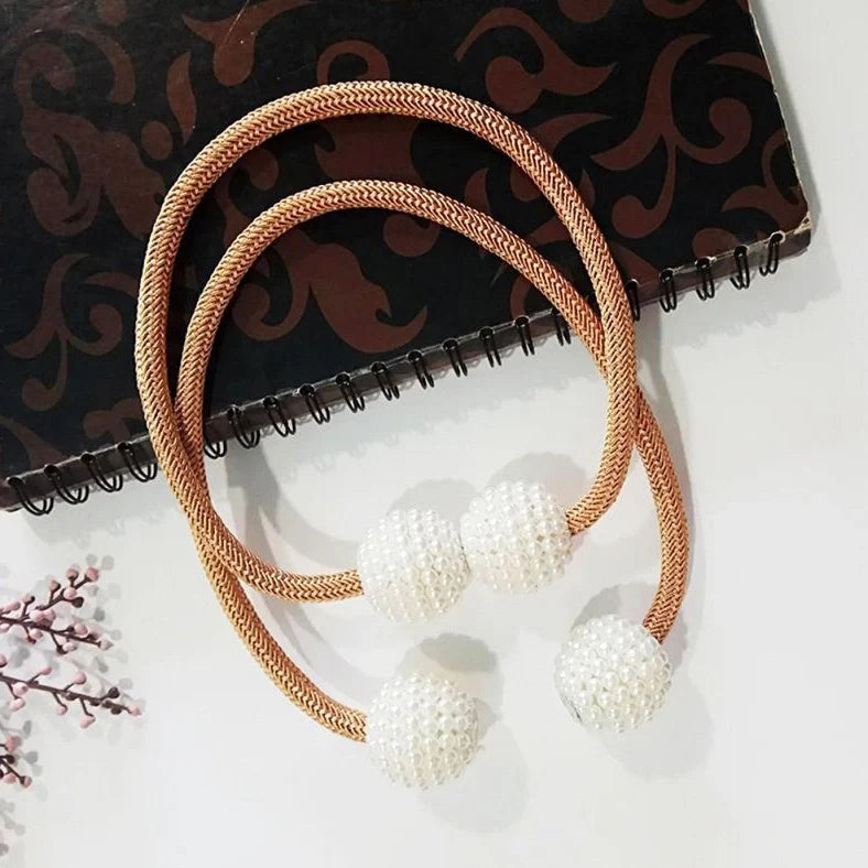 Magnetic curtain tiebacks with white pearl beads and fabric loops holding gathered curtain