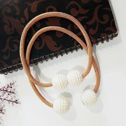 Magnetic curtain tiebacks with white pearl beads and fabric loops holding gathered curtain