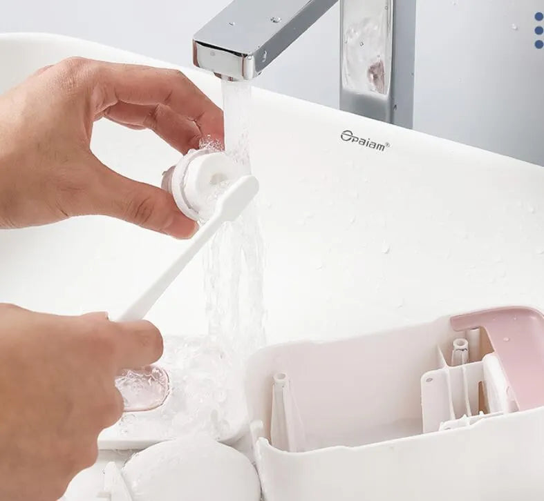 Automatic wall-mounted toothpaste dispenser in blue, grey, and pink colours with LED touch sensor.