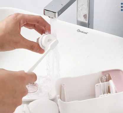Automatic wall-mounted toothpaste dispenser in blue, grey, and pink colours with LED touch sensor.