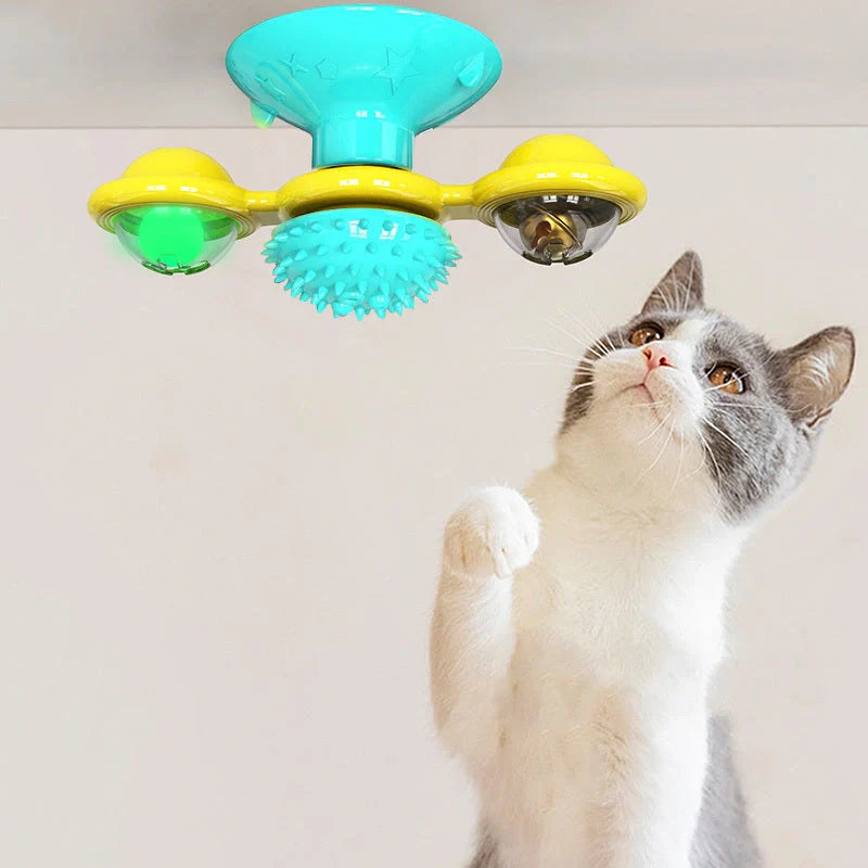 Cat playing with rotating windmill toy featuring luminous balls and suction base