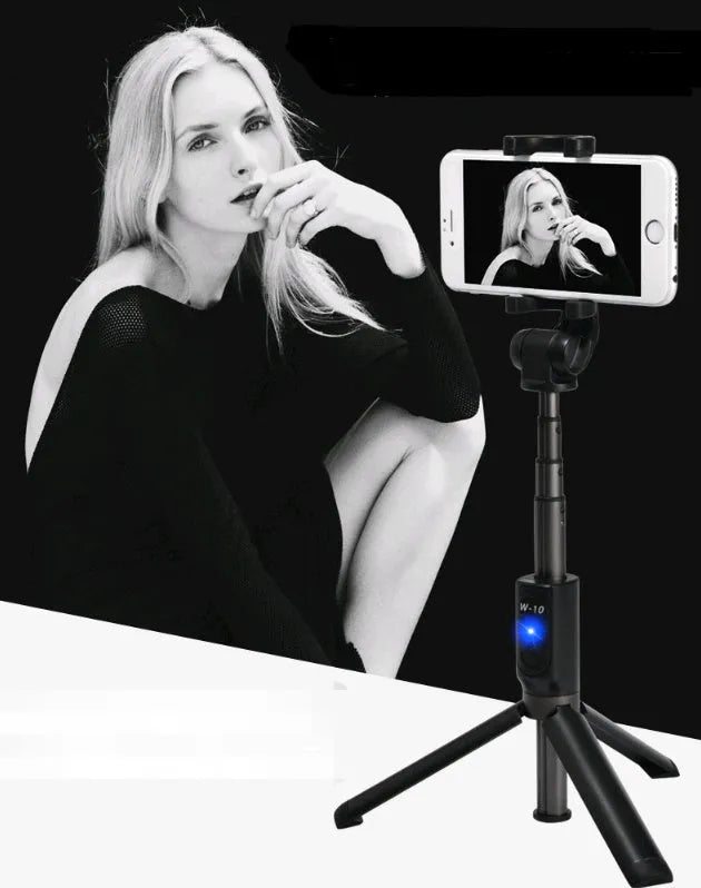 Aluminium tripod selfie stick with extended phone clip and Bluetooth remote on a table