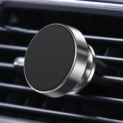 Silver aluminium alloy magnetic car phone holder with rotating ball head mounted on a car air vent.