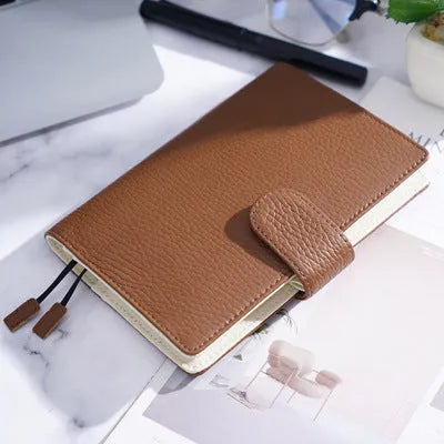 Close-up of a hand-embossed lychee pattern on an off-white A6 cowhide leather notebook with loose-leaf binding.