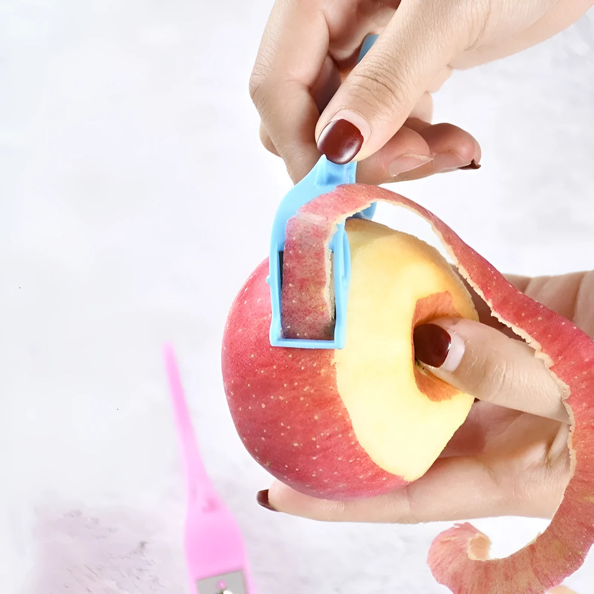 Multifunctional fruit peeler with finger ring grip and stainless steel blade in pink, blue, orange colours