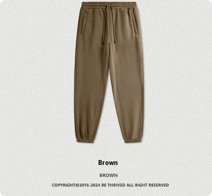 Man wearing solid colour cotton velvet sweatpants with an ankle banded design in a dark grey shade.