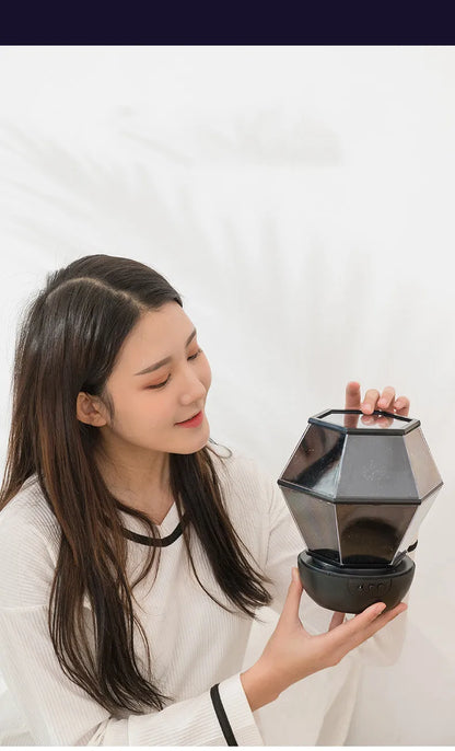Children's rotating star projector night light showing blue, green, and yellow stars projected on a ceiling.