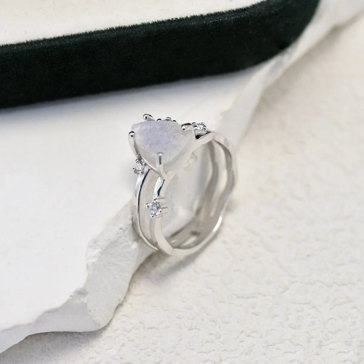 S925 sterling silver ring with an irregular triangular bezel holding a genuine cabochon moonstone, on a model's finger.