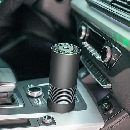 Compact black car air purifier with aluminium alloy and ABS construction, shown next to a car USB port.