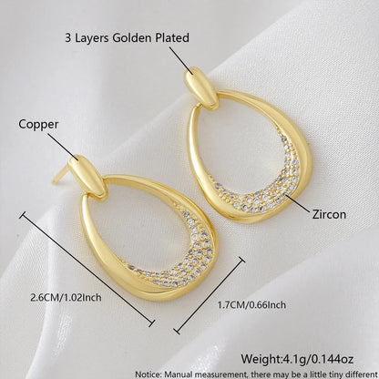 Women's yellow gold geometric drop earrings with oval and round elements on a white background.