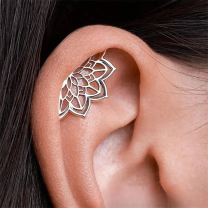 Close-up of a geometric spider web design on a gold-toned metal stud earring.