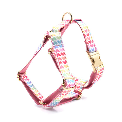 Pink dog harness with gold buckle and heart-shaped stones on a chest and back strap.