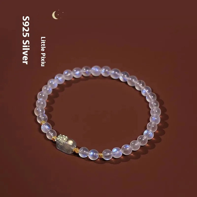 Close-up of a women's moonstone bracelet with an animal or Zodiac motif on a blue background.