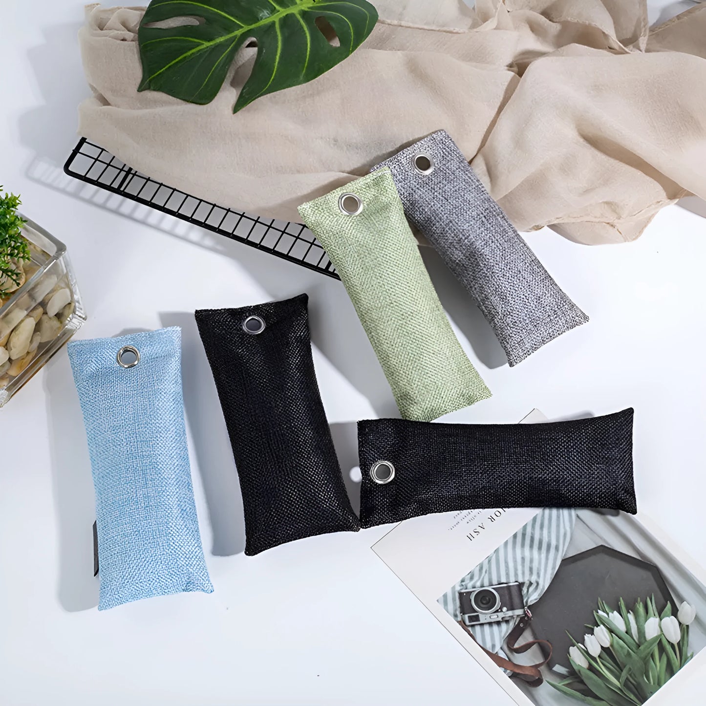 Set of black, green, grey, and blue rectangular bamboo charcoal deodorising bags on a white surface.